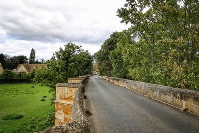 Road by trees against sky