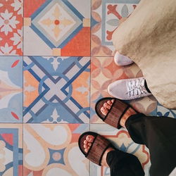 Low section of man wearing shoes on tiled floor