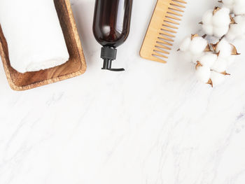 Bottle container with pump mock up, towel, wooden hair comb on white marble background.