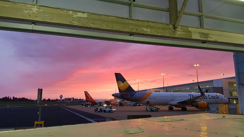 Airplane on airport runway against sky during sunset