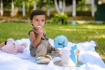 Portrait of cute girl blowing bubbles while sitting on bed at park