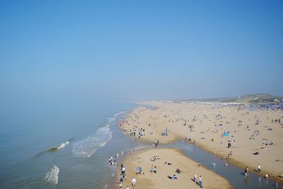 Panoramic view of people on beach against clear blue sky