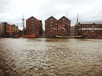 River by buildings in city against sky