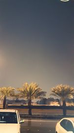 Road by trees against clear sky during sunset