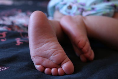 Low section of baby lying on bed