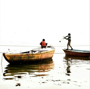 People on boat sailing in sea against clear sky