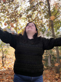 Beautiful young woman standing against trees