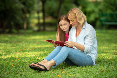 Young woman using phone while sitting on grass