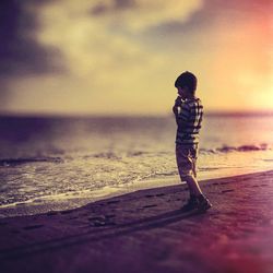 Woman standing on beach at sunset