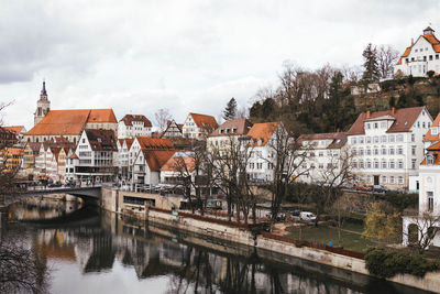 Houses by river in town against sky