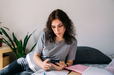 Portrait of young woman using mobile phone at home