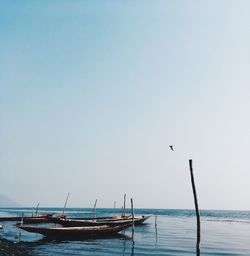 Boats moored on sea against clear sky