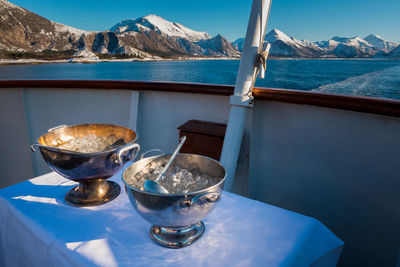 Close-up of water in container on table by sea against sky