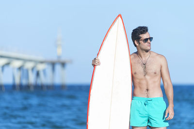 Young man standing by sea against sky