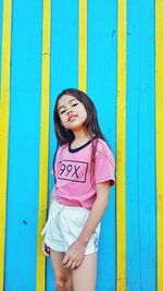 Portrait of happy girl standing against blue wall