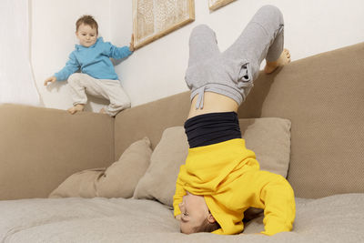 Two active, little kids doing gymnastic handstand exercise in living room. 