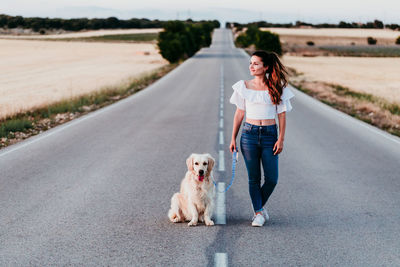 Woman standing with dog on road against sky