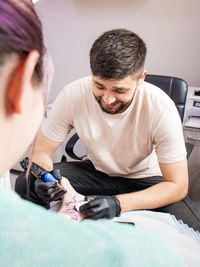 Tattoo artist in black gloves working on a tattoo on the leg of a young woman tattooing a tattoo 