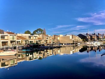 Buildings by lake against blue sky