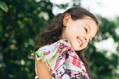 Close-up of smiling girl against tree