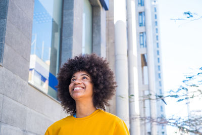 Portrait of smiling young woman standing against building