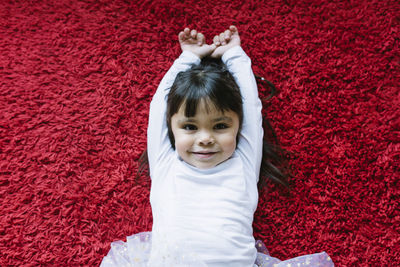 Portrait of a smiling girl lying on red carpet
