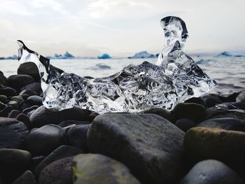 Close-up of pebbles on beach against sky