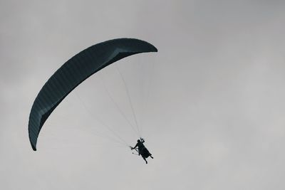 Low angle view of person paragliding against sky