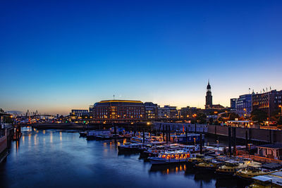 River amidst illuminated buildings against clear sky