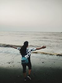 Rear view of man on beach against sky