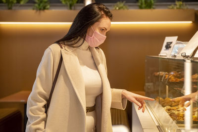 Woman looking at display while standing in store during covid-19