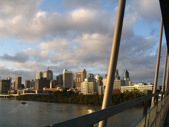 Modern buildings by river against sky in city