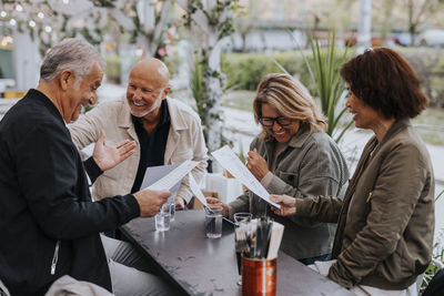 Happy male and female senior friends enjoying while reading menu card at restaurant