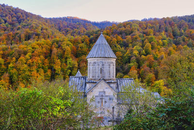 Trees by building against sky during autumn