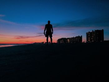 Silhouette man on city against sky at sunset