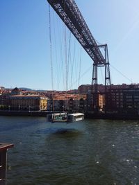 Bridge over river against sky in city