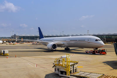 Airplane on airport runway against sky