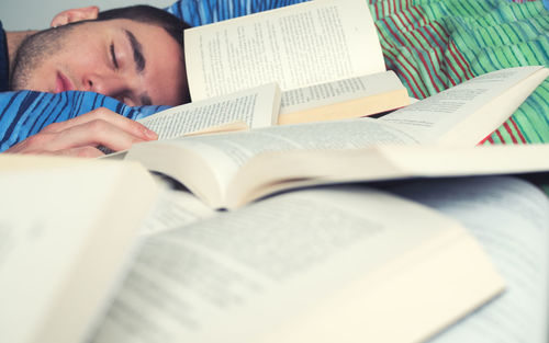 Close-up of man sleeping next to open books