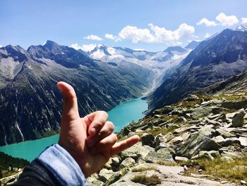 Midsection of person hand on rock against sky