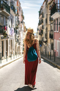 Rear view of young woman standing against buildings in city