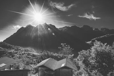 Sun shining through clouds over mountains