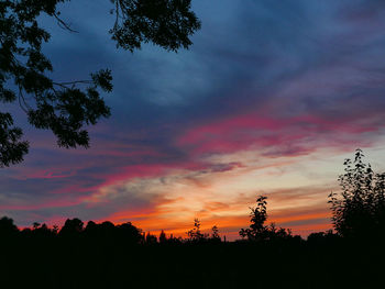 Low angle view of silhouette trees against dramatic sky