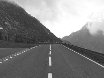 Empty road by mountains against sky