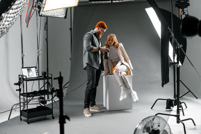 Professional fashion photoshoot. photographer adjusting model's pose in studio light setup