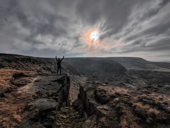 Man standing on rock on land against sky