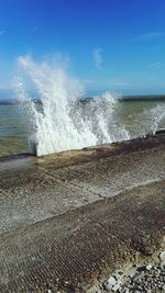 Close-up of waves splashing on beach against sky