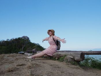 Woman with arms raised against clear blue sky