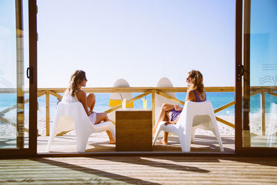 Friends relaxing on wooden deck by beach