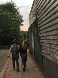 Rear view full length of sisters walking on sidewalk