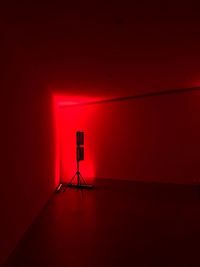 Illuminated red light against wall at night